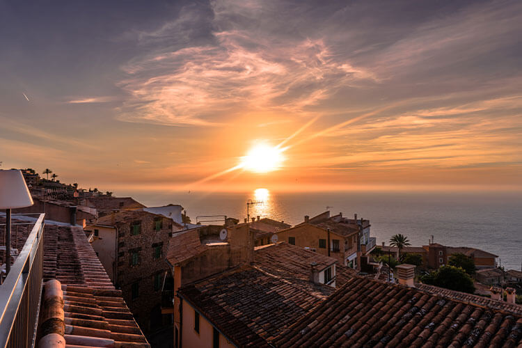 Buildings by sea against sky during sunset in Banyalbufar